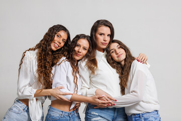Group of four happy friends wearing casual outfits posing together and expressing friendship and joy.