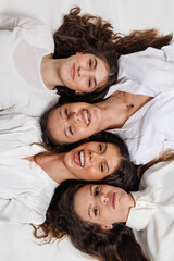 Group portrait of four young women smiling happily while lying together in a creative and harmonious arrangement