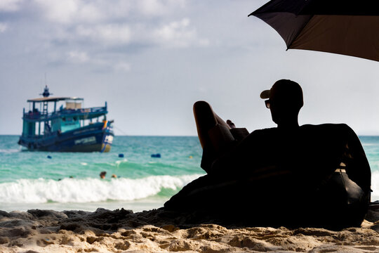 Silhouette of a man relaxing under a parasol on a sea beach