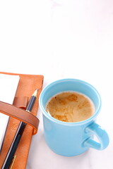 Opened schedule planner, diary, notebook with cup of Coffee on white table
