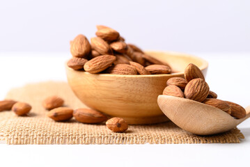 Raw almond nut seed in wooden bowl and spoon on white background