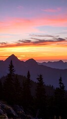 Fototapeta premium Mountains at dawn display a vibrant sky filled with orange, yellow, and lavender hues at daybreak.