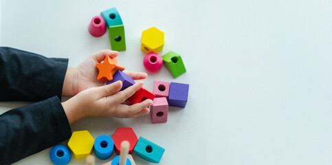 Top view of 3 year old girl having fun playing with colorful geometric shape wooden blocks...