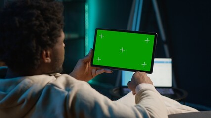 African american freelancer uses copy space display on tablet to work from the comfort of his home, sitting on the couch in his trendy stylish living room. Happy young adult on web. Camera A.