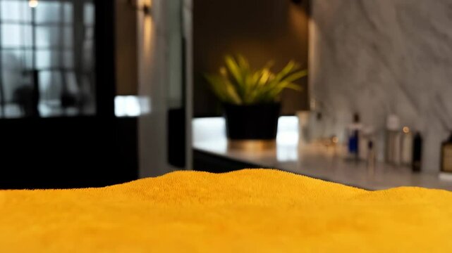 Stack of four folded colorful plush towels: yellow, gray, black, and red in hotel bathroom with candles