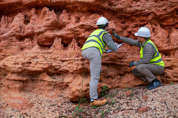 Expert geologists and explorers are working together to examine the rock layers in a mountain to determine the minerals in the rock layers.