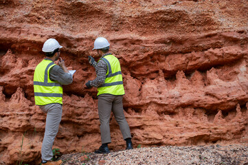 Expert geologists and explorers are working together to examine the rock layers in a mountain to determine the minerals in the rock layers.