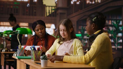 Preteens girls and their professor collaborating on schoolwork at the library, focused on academic materials to write a good essay. Students collect extra information with private lessons. Camera B.