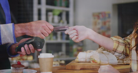 Image of financial data over hands of caucasian people using payment terminal