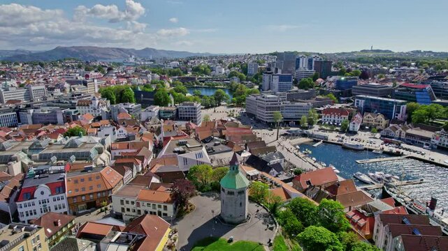 Forward-moving drone flies over Valberg Tower and reveals Breiavatnet and the surrounding Stavanger cityscape in sunny weather.