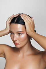 Fototapeta premium Beautiful Latina Woman Touching Her Hair In Minimalist Studio 