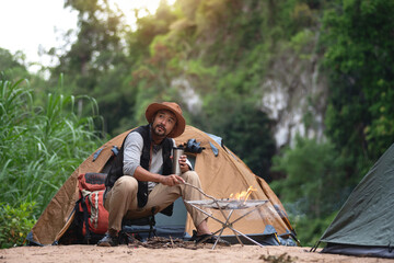 Man relax in front of his tent, add dry branches to the fire for warmth in the evening. Adventure...