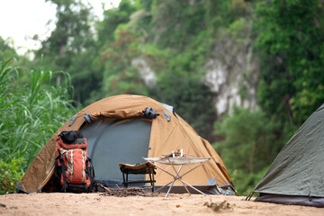 A hiking backpack leans against the side of a tent at camp.