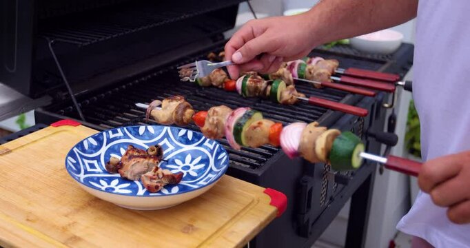 Man Grilling Meat and Vegetable Skewers on Cozy Patio &ndash; Close-Up of Hands Cooking Outdoors. Real Life Family Weekend, Outdoor Cooking, Food Prep. Summer Backyard BBQ