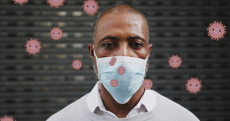 Image of falling covid 19 cells over african american men wearing face mask