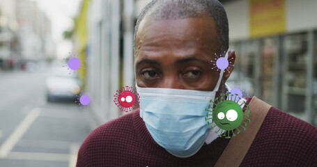 Image of falling covid 19 cells over african american men wearing face mask