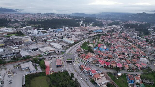 4K 60fps morning drone view of Cuenca&rsquo;s industrial park, showing factories, warehouses, highway access, and parts of the city surrounded by the Andean landscape.