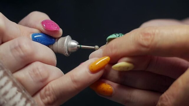 Beautician removing nail polish with electric nail drill