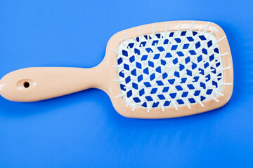 A hairdressing brush on a bright blue background, ideal for product photos. Its ergonomic design and contrasting color combination create an attractive visual effect for advertising