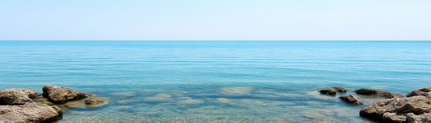 Fototapeta premium Serene blue ocean with clear sky and rocks.