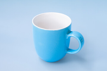 Vibrant blue ceramic mug with glossy finish is placed matching blue background, creating harmonious and calming visual effect. mug simple design and smooth surface make it ideal for everyday use