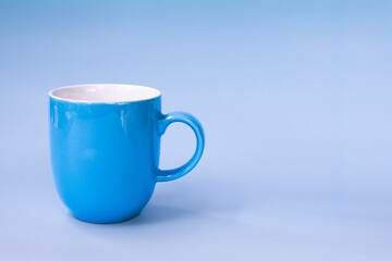 Vibrant blue ceramic mug with glossy finish stands against matching blue background, creating calming and cohesive visual