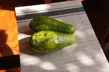 Two avocados on a wooden and glass table with a rustic and country background
