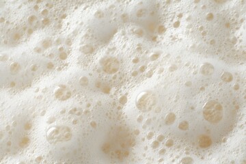 Close-up shot of frothy beer head, showcasing its texture and bubbles.  The creamy foam creates a visually appealing surface with varying bubble sizes