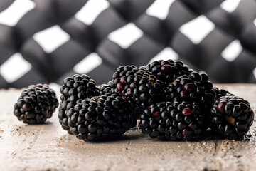 Glossy ripe blackberries on rustic board with geometric bokeh