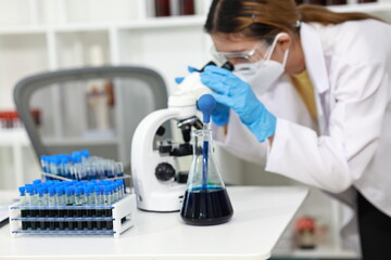 Scientist in laboratory analyzes blood sample using microscope and test tubes. Biotechnology,...