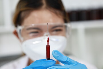Scientist in laboratory analyzes blood sample using microscope and test tubes. Biotechnology,...