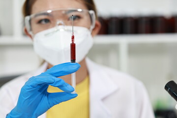 Scientist in laboratory analyzes blood sample using microscope and test tubes. Biotechnology,...