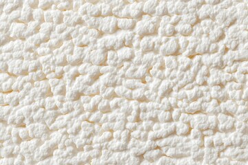 A close-up view of a textured stucco wall surface, showcasing its uneven and granular appearance