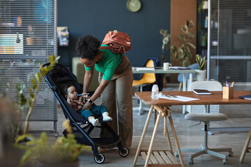 Mother helping child in stroller in a modern cafe setting, surrounded by contemporary furnishings...