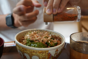 Sprinkling Chili Powder on Gyudon (Beef Bowl) &ndash; Japanese Cuisine.
