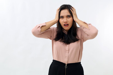 Naklejka premium Shocked and anxious young Asian woman in panic, holding hands on head and worried, looking at camera, standing frustrated and afraid on white background.