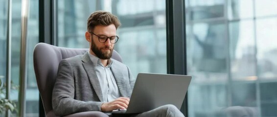 A businessman uses a laptop while sitting in a contemporary workplace, exuding confidence and professional. - Powered by Adobe