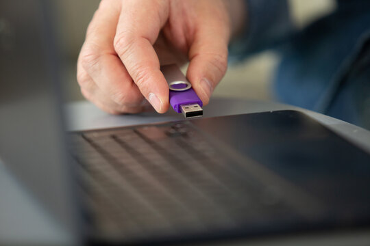 male hand connects usb flash drive in a laptop device