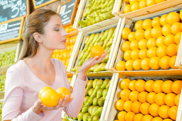 Obraz premium Lady holding oranges in greengrocers