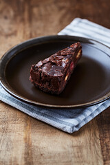 Piece of Chocolate Cake on a Plate. Rustic stone background. Copy space.