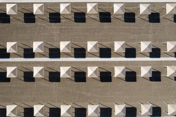Perfect geometry of shadows and umbrellas on a deserted beach seen from above