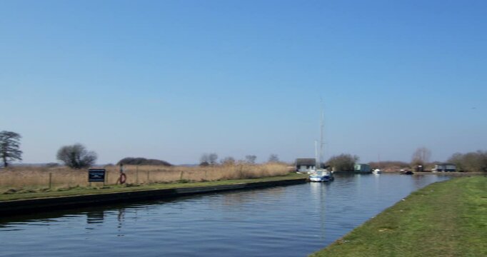 Panning shot left to right looking down a inlet on the river Thurne at the village of Thurne, with Thurne mill in background.