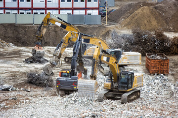 Excavators and heavy construction machinery are operating during the demolition of a former...