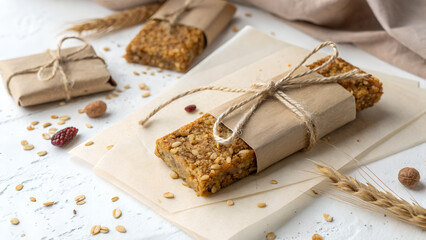 Fototapeta premium Homemade Granola Bars Wrapped in Paper with Twine on White Background Healthy Snack Rustic Style Close Up Top View
