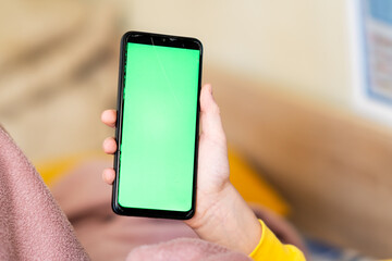 Child's hands holding green screen phone