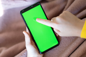 Child's hands holding green screen phone