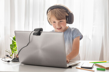 Schoolboy enjoying remote learning with headphones and laptop at home