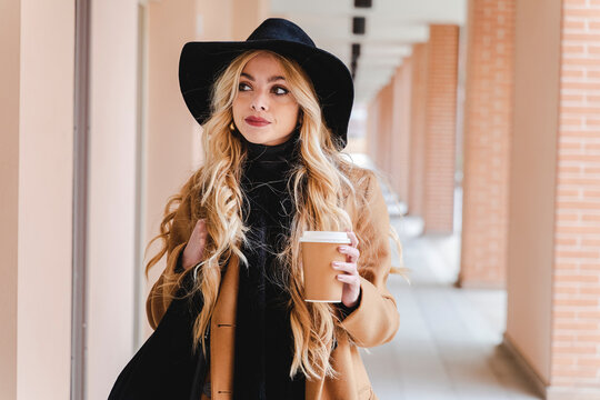 Woman with long hair holding coffee cup while looking away