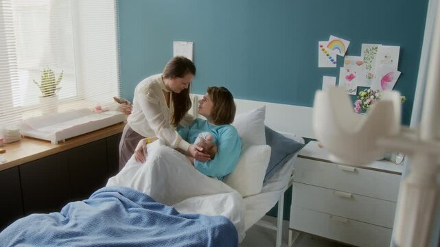 Mature Caucasian woman visiting her daughter and newborn granddaughter in maternity hospital, copy space