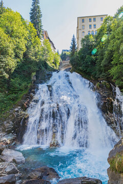 Gastein Waterfall in Bad Gastein, Austria, surrounded by lush greenery and Belle Epoque architecture.